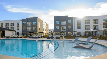 A swimming pool in front of a row of modern apartment buildings.
